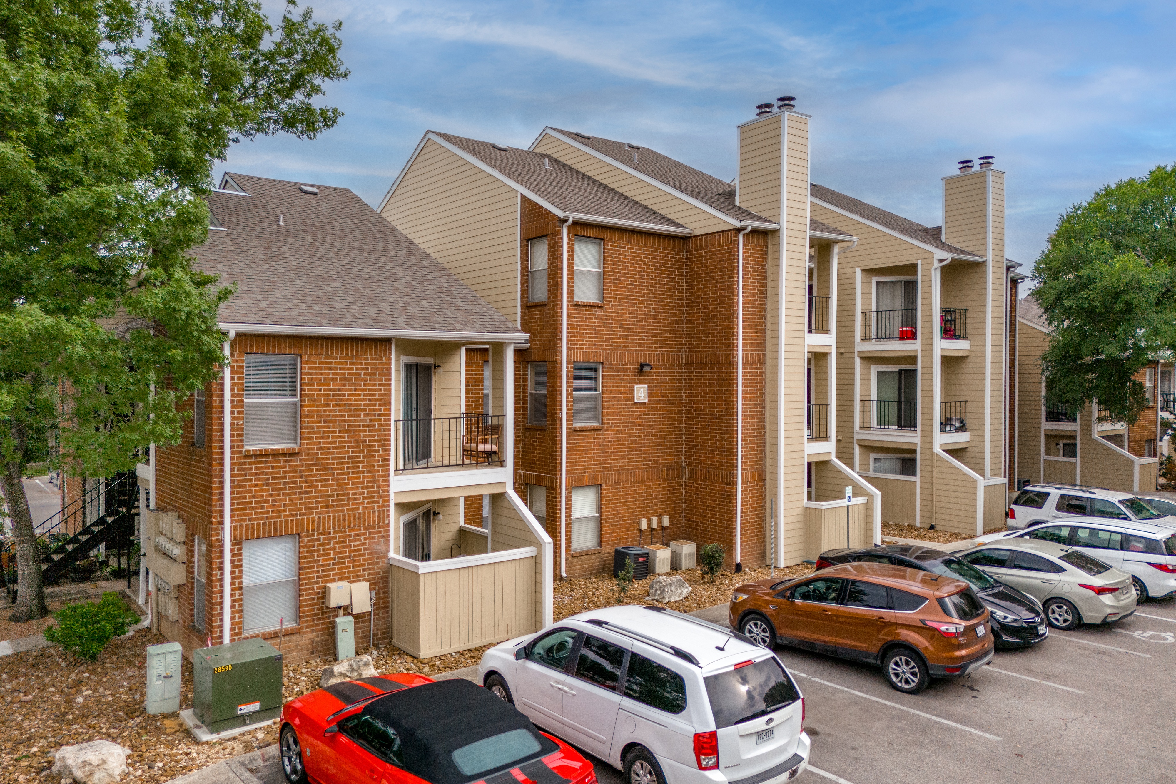 A parking lot with cars and apartment buildings in the background.